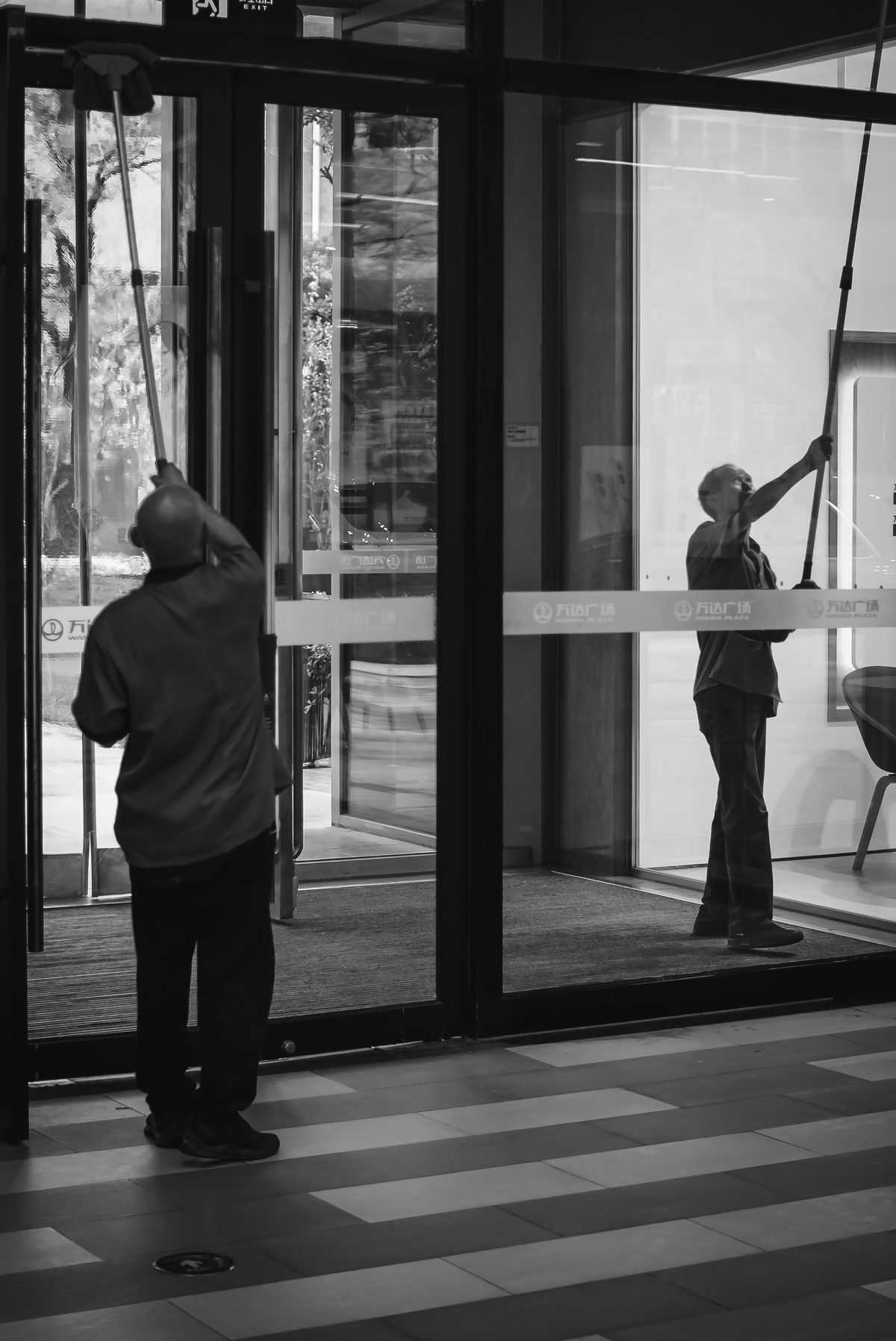 Cleaning workers maintaining glass doors in a commercial building